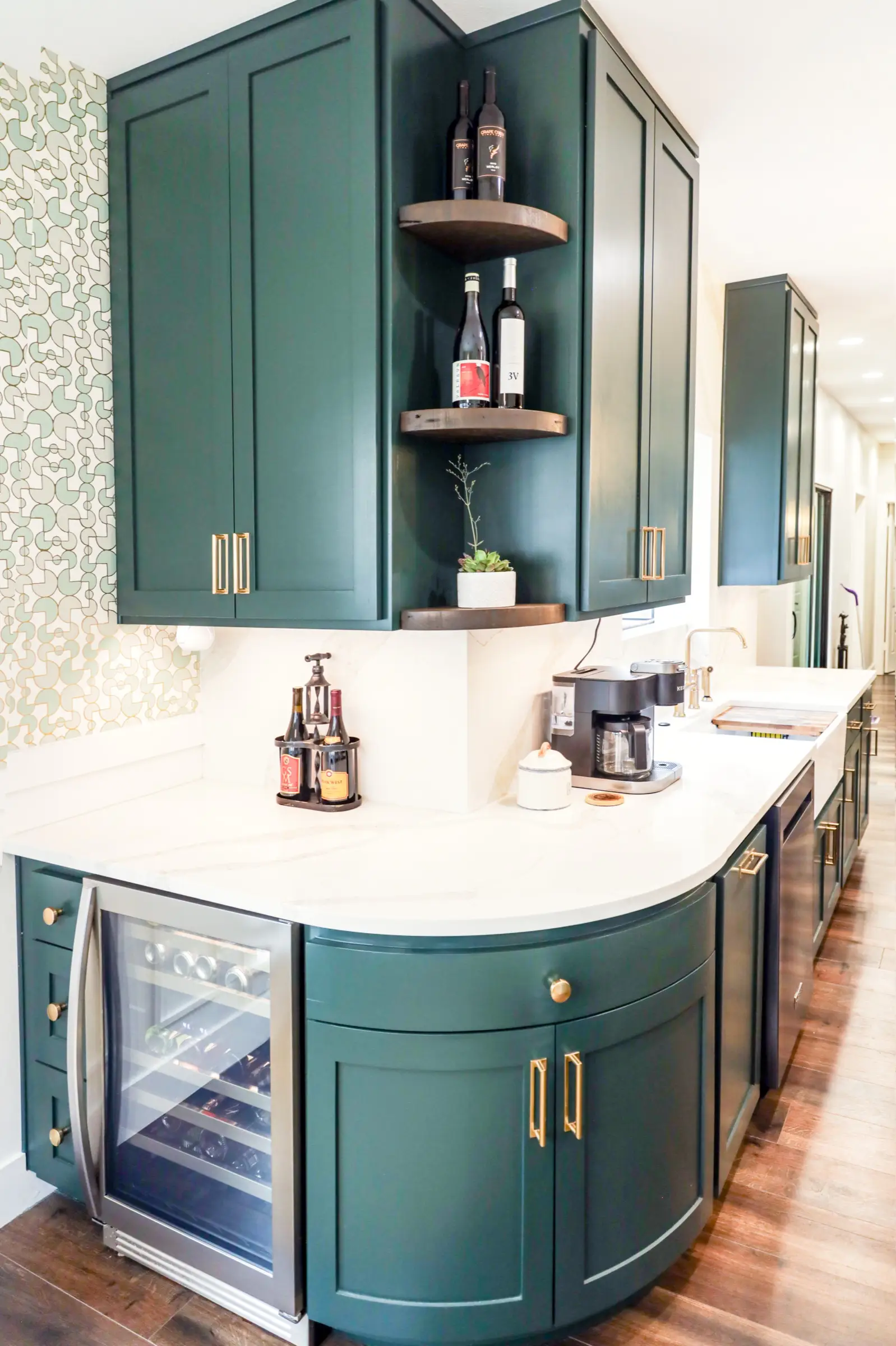 Interior design wide shot of a green kitchen island with open wood shelving and styled decor.